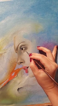 a woman is painting a portrait of a woman's face