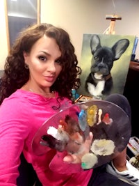 a woman holding a painting of a french bulldog